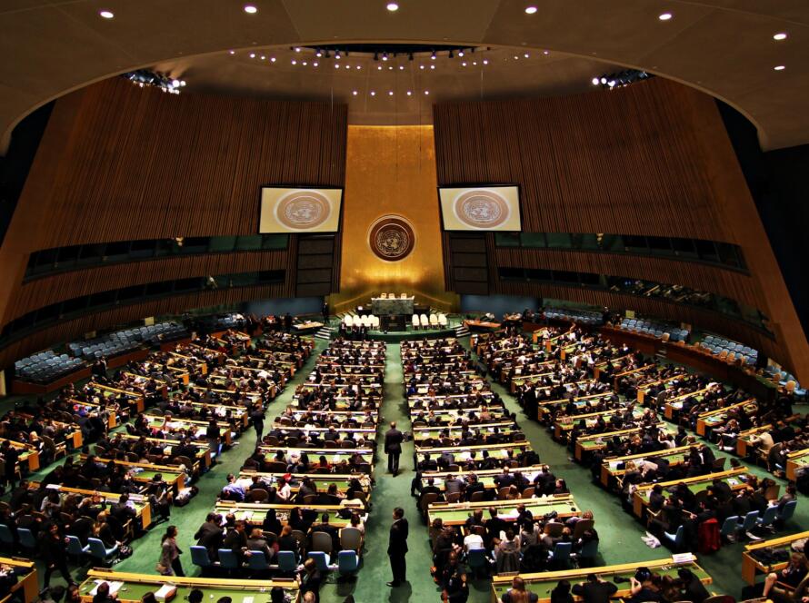 Totale des Generalversammlungssaals der Vereinten Nationen in New York mit goldener Stirnwand, UN-Emblem und Delegiertenreihen